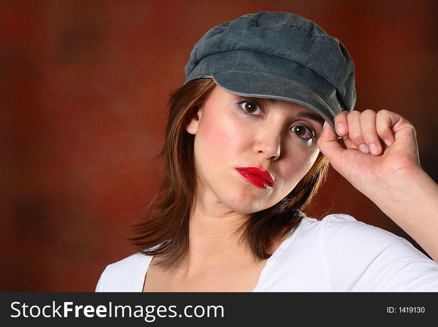 Brunette with grey cap and white shirt in front of red backdrop. Brunette with grey cap and white shirt in front of red backdrop