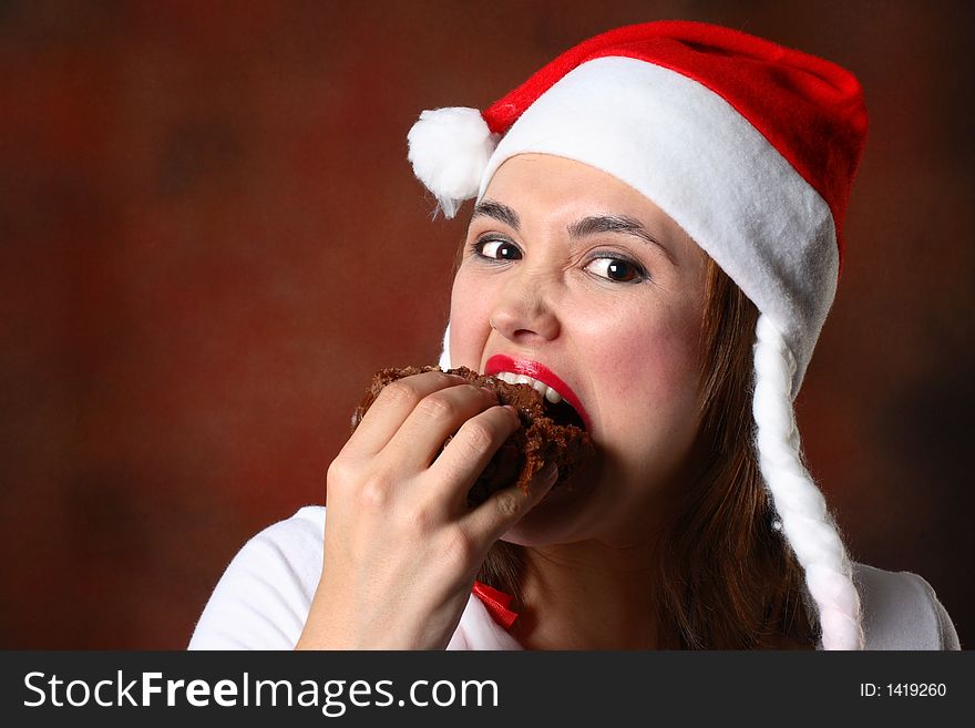 Brunette woman with santa hat eating a chocolate cake. Brunette woman with santa hat eating a chocolate cake