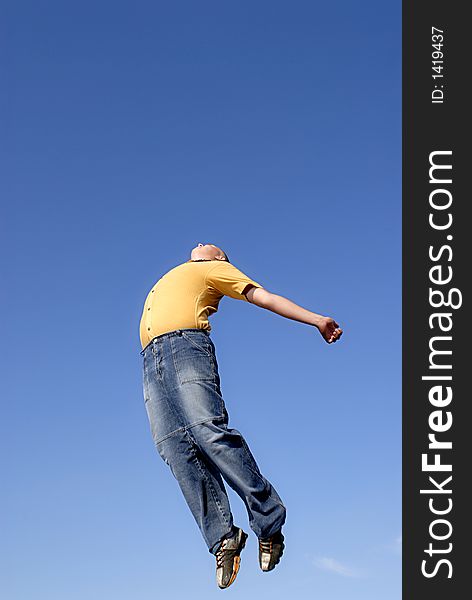 Young boy happily jumping against blue sky. Young boy happily jumping against blue sky.