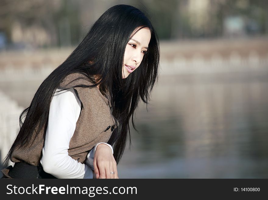 A young Asian girl looking out over a river pensively. A young Asian girl looking out over a river pensively.