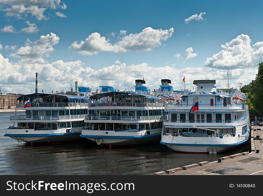 Several white cruise liners are moored in river port. Saint-Petersburg, Neva river. Blue sky with clouds.