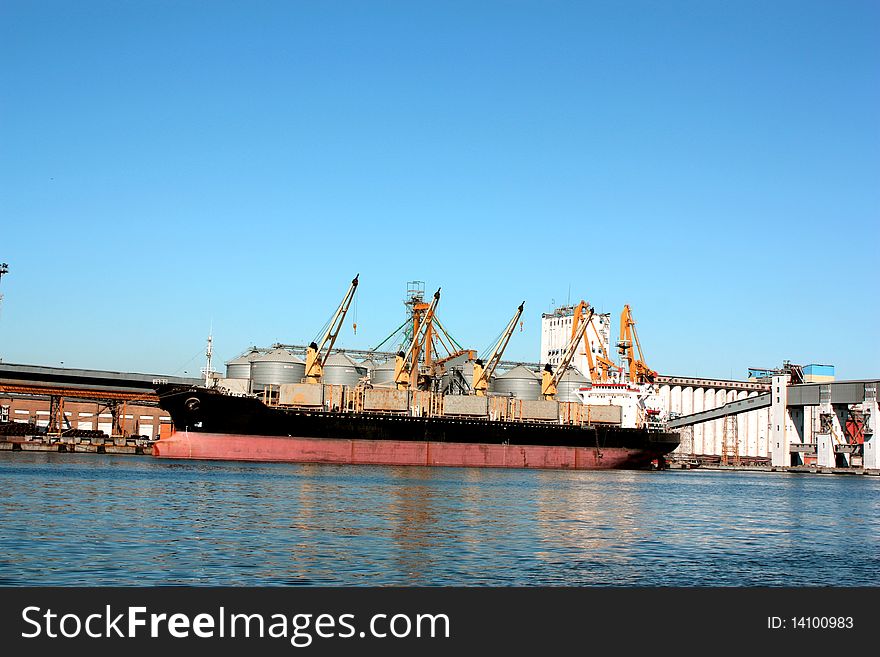 Ship receives cargo at the port, loading cranes being, but rather in the sea;. Ship receives cargo at the port, loading cranes being, but rather in the sea;