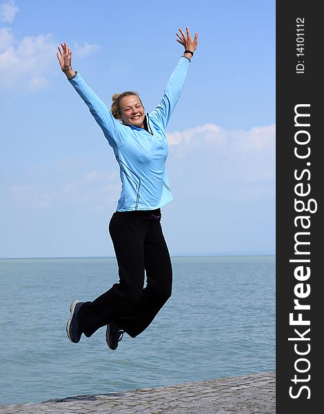Happy young girl jumping  on the shore