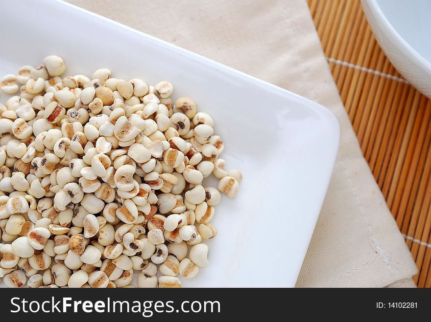 Dried barley seeds on white plate. Commonly used as a food ingredient in many Chinese cuisine and desserts. For food and beverage, and diet and nutrition concepts.