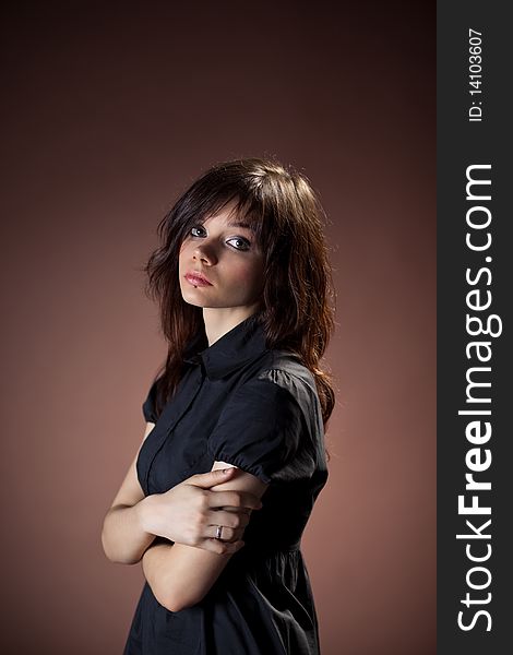 A young girl in a black dress on a brown background. A young girl in a black dress on a brown background