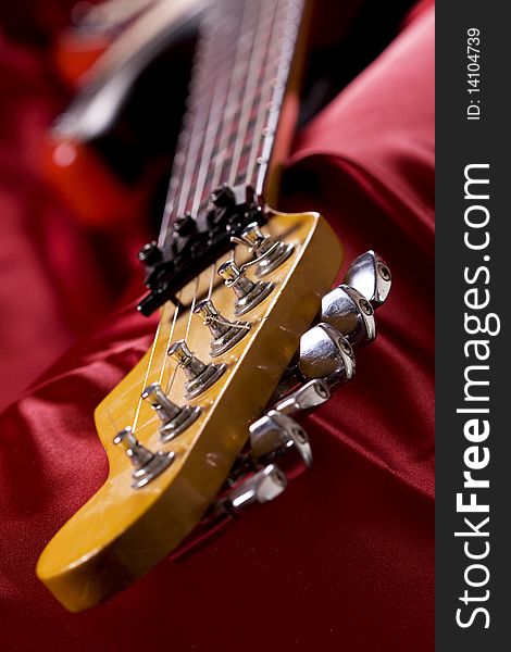 Close-up on an electric guitar on red satin background. Close-up on an electric guitar on red satin background