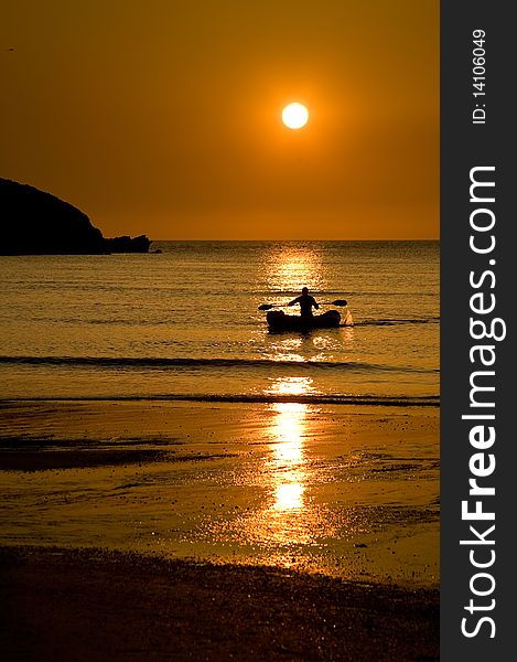 Image of a kayak in the ocean at sunset