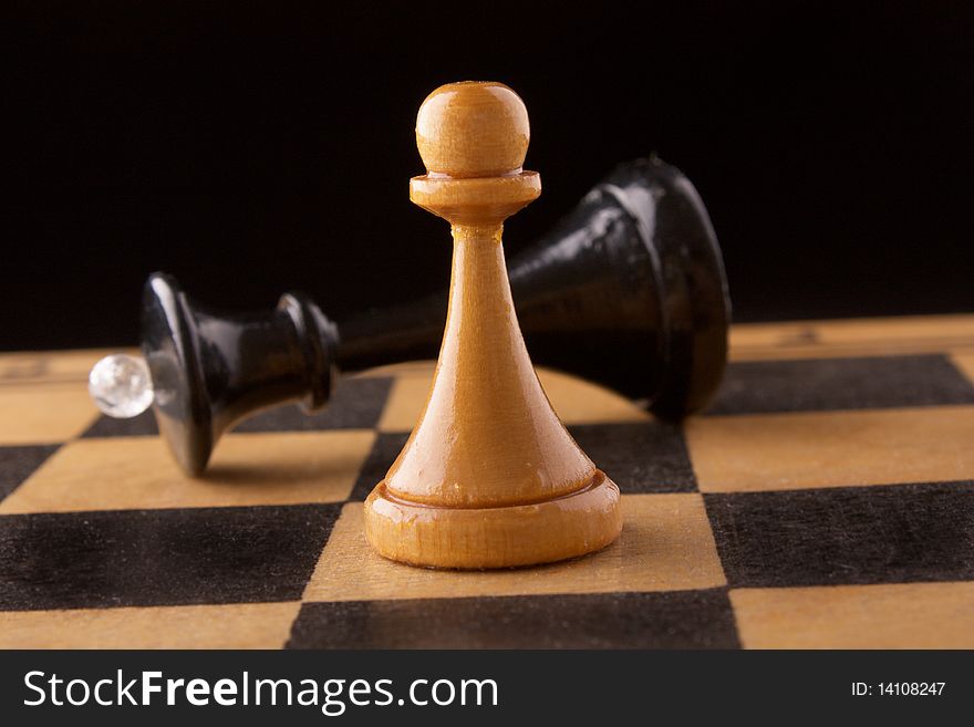 Black chess queen lays on a chessboard, black background. Black chess queen lays on a chessboard, black background