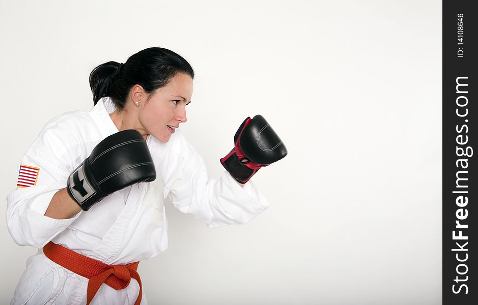 Beautiful young woman in a boxing stance wearing a white martial arts uniform and boxing style gloves. Beautiful young woman in a boxing stance wearing a white martial arts uniform and boxing style gloves.