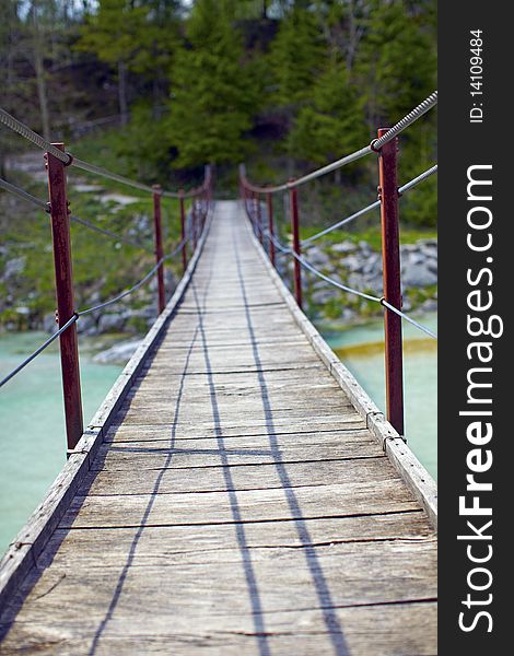 Hanging wooden suspension bridge over a river. Hanging wooden suspension bridge over a river.