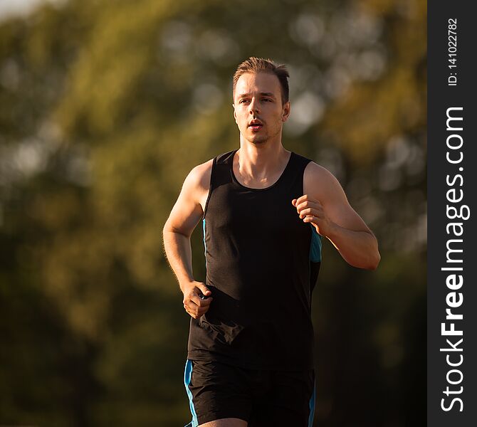 Handsome youg runner jogging outdoors on a lovely summer evening