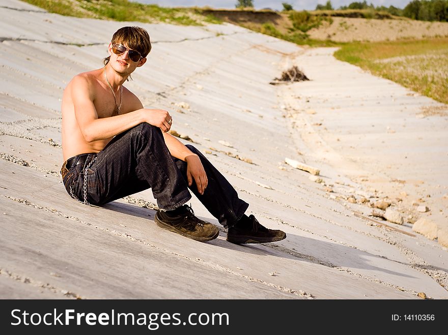 Picture of a young guy, relaxing on a beton blocks. Picture of a young guy, relaxing on a beton blocks