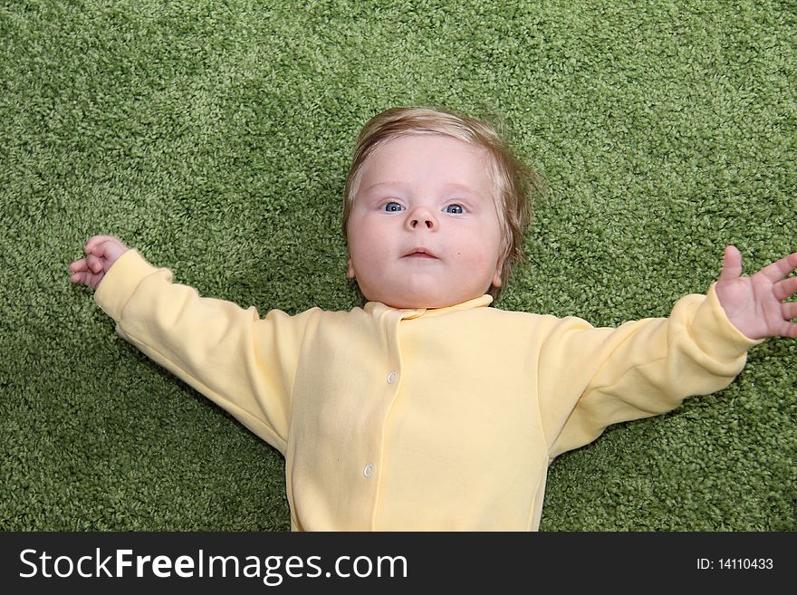 Nice baby boy greetings with open arms on a green fluffy cover