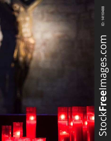 Religious statue with candles in foreground form church interior. Religious statue with candles in foreground form church interior