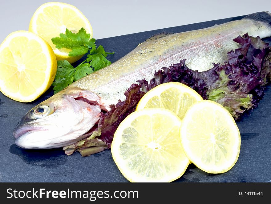 Fresh whole rainbow trout, decorated with salad leaves and lemon