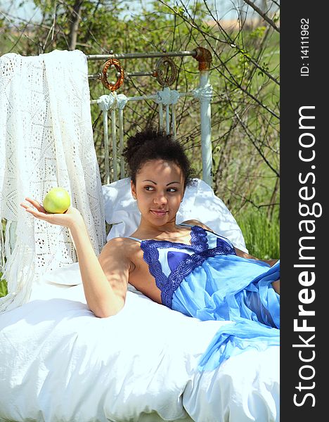 A beautiful mixed race African American girl with apple in the garden