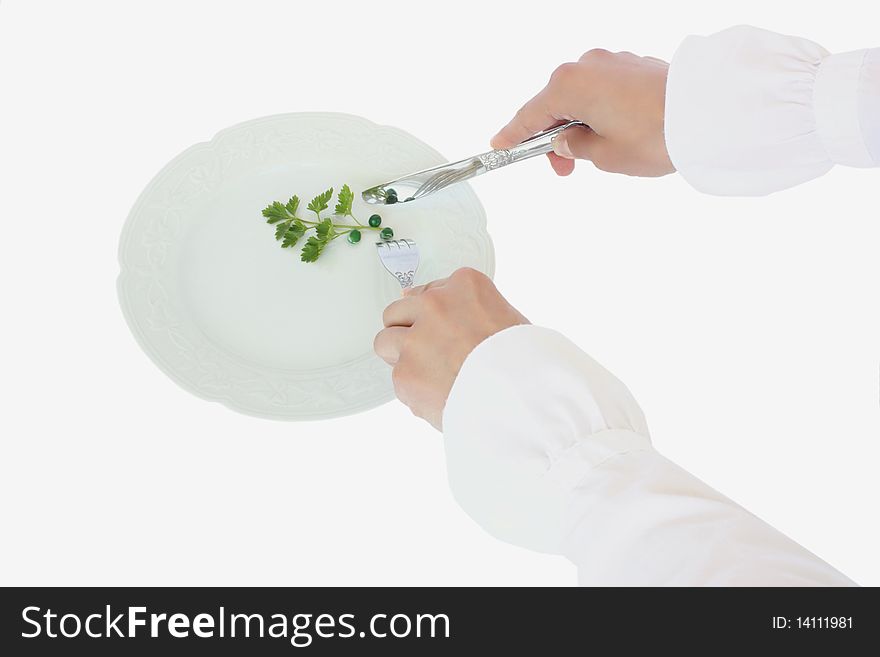 A dinner plate with peas and parsley and hands with fork and knife isolated on a white background