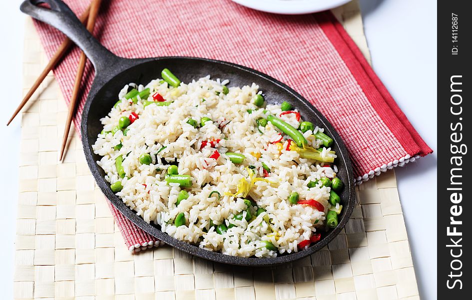 Rice and mixed vegetables stir fried in a skillet. Rice and mixed vegetables stir fried in a skillet