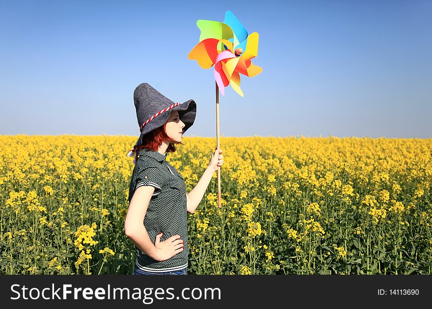 Girl in cap with wind turbine at rape field. Odessa, Ukraine.