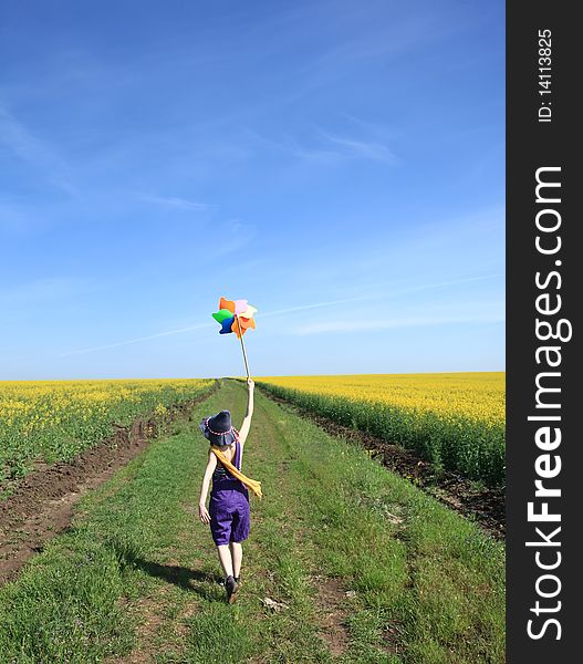 Girl with wind turbine at rape field.