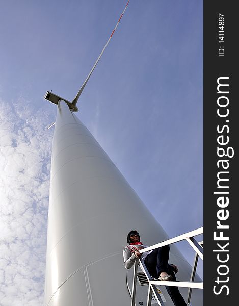 An image of young girl staying on stairs to wind turbine. An image of young girl staying on stairs to wind turbine