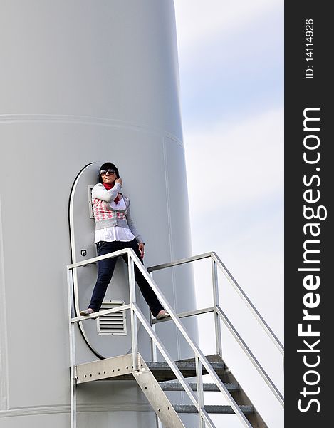 An image of young girl staying on stairs to wind turbine. An image of young girl staying on stairs to wind turbine