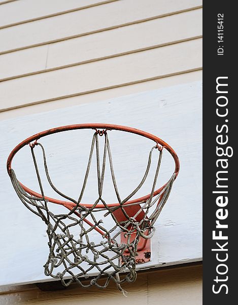 A basketball hoop on a white wall. It is really worn