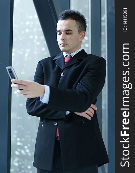 A young and handsome business man with a mobile phone. Image taken in a modern office. A young and handsome business man with a mobile phone. Image taken in a modern office.