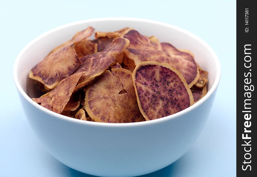 Sweet potato crisps in a bowl isolated against a blue background