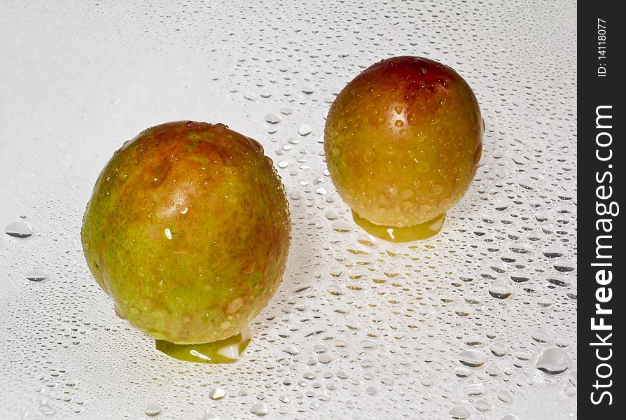 Two fruit of apricot with leaves is on a white background.