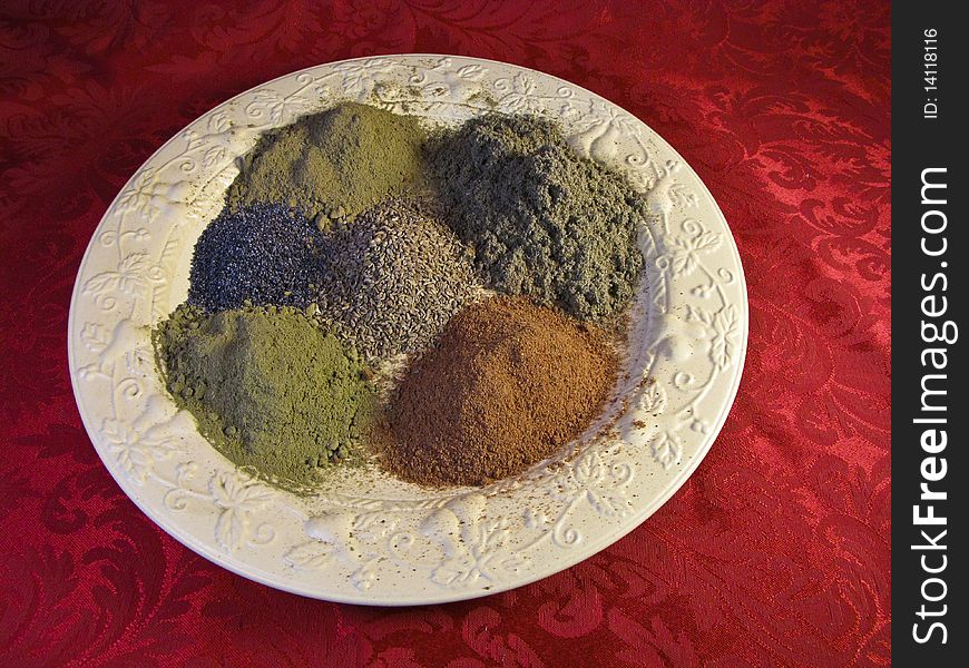 Various spices on a yellow plate with a red textile background