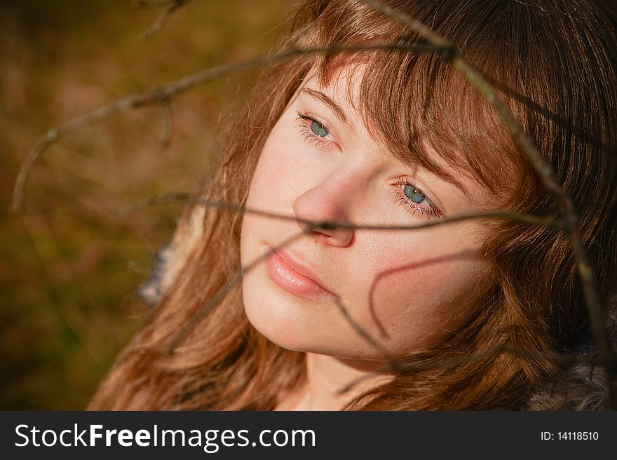 Portrait of a beautiful young woman with blue eyes, she is dreaming, there are shadows from the branch on her face. Portrait of a beautiful young woman with blue eyes, she is dreaming, there are shadows from the branch on her face