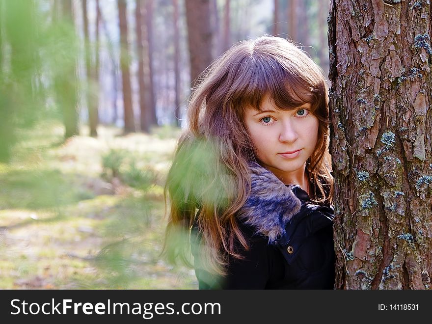 Young beautiful woman standing near the tree in the forest, it is spring and the sun is shining. Young beautiful woman standing near the tree in the forest, it is spring and the sun is shining