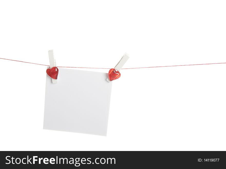 Sheet of white paper hanging from a rope with clothespins with a red heart. Isolated on white background. Sheet of white paper hanging from a rope with clothespins with a red heart. Isolated on white background