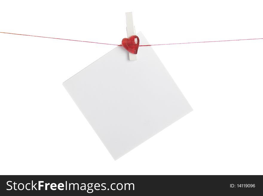 Sheet of white paper hanging from a rope with clothespins with a red heart. Isolated on white background. Sheet of white paper hanging from a rope with clothespins with a red heart. Isolated on white background