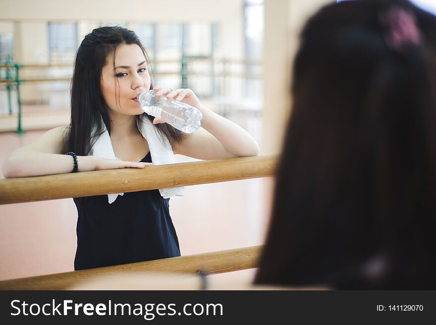 Young healthy woman drinking water in fitness
