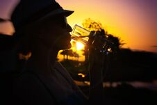 Woman With White Hat And Pink Sunglasses With Nice Reflection Of Palm Trees And Sunset Drinking Fresh Pure Water Stock Photos