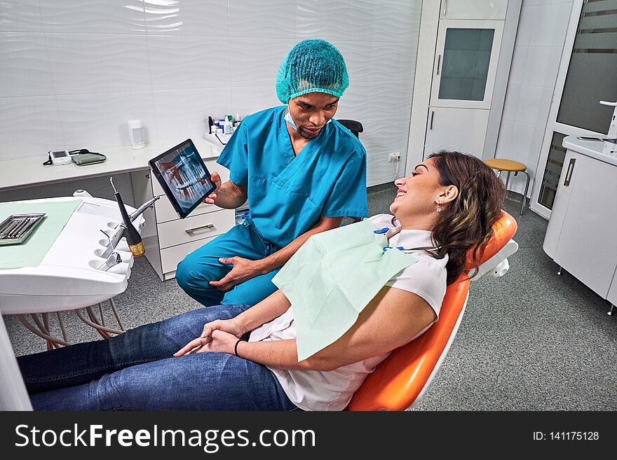 African male dentist explaining x-ray to the patient sitting in the chair