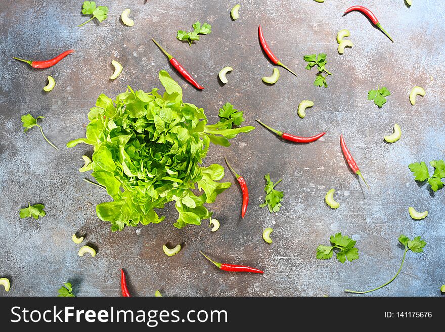 Pattern made of fresh vegetables and big lettuce buncheson dark stone background.