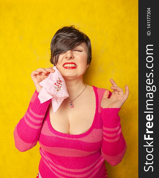 Allergy Woman Wear Pink Warm Sweater standing with runny nose holding a handkerchief on yellow studio solid background alone with emotions