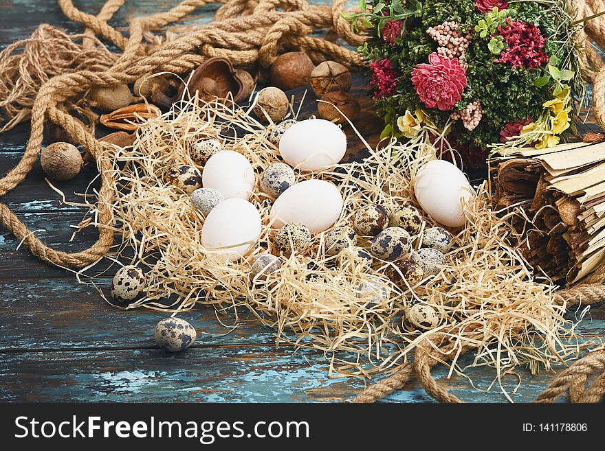 White chicken eggs and quail eggs near dry flowers. Eggs For Easter.