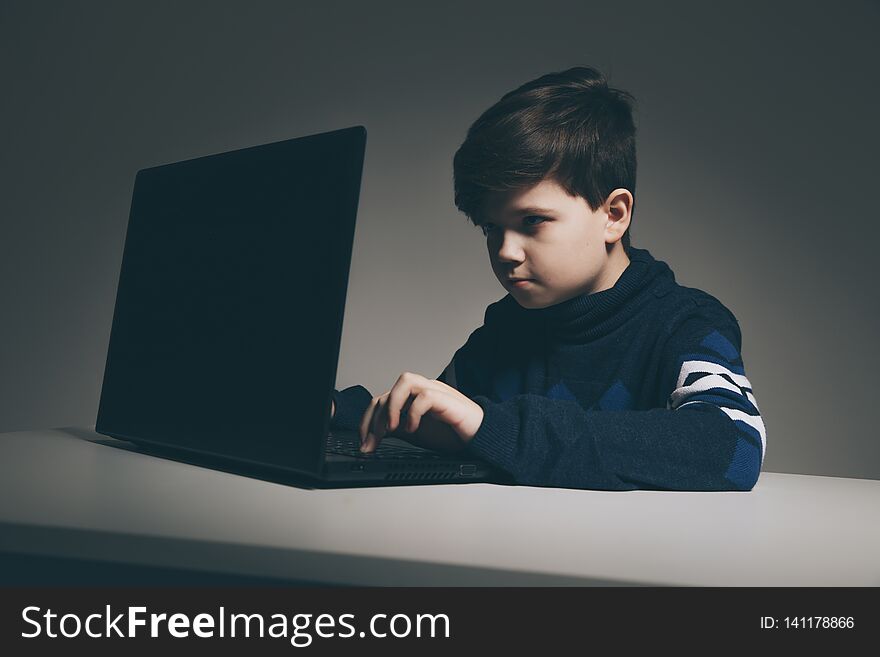 Photo Of Nice Boy In Sweater Sitting Infront Of The Computer Doing Homework.