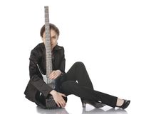 Seated Girl With A Black Electric Bass Guitar Royalty Free Stock Photography
