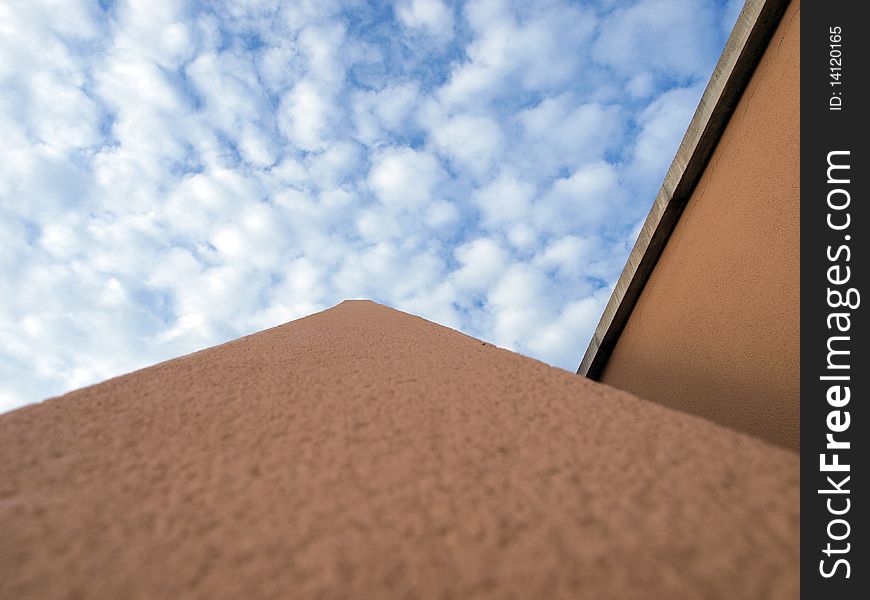 Close up view on part of building that points directly towards the heavens, with a blue sky with broken clouds. Close up view on part of building that points directly towards the heavens, with a blue sky with broken clouds.