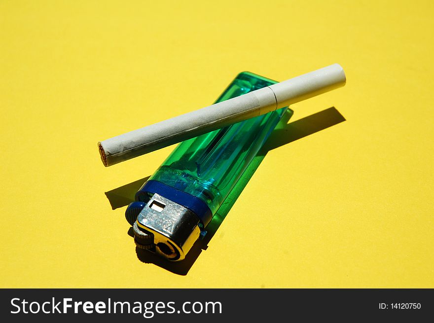 Close up of cigarette and lighter with yellow background. Close up of cigarette and lighter with yellow background