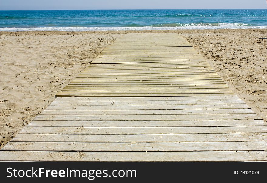 Wooden footbridge in the sand of a beach for access to the sea. Wooden footbridge in the sand of a beach for access to the sea