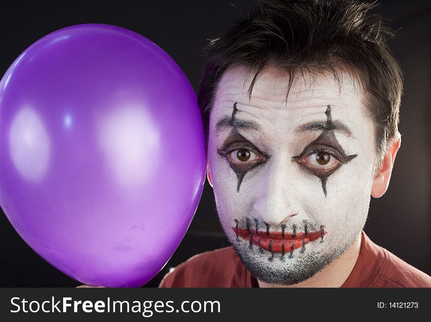 Clown with a balloon looking at camera on a black background. Clown with a balloon looking at camera on a black background