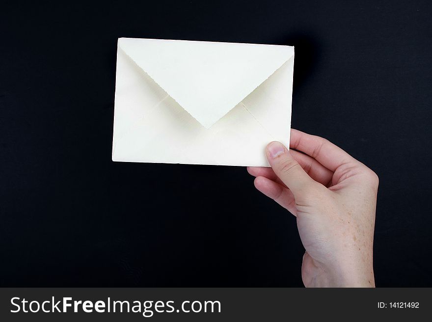 Hand holding a white envelope with dark background