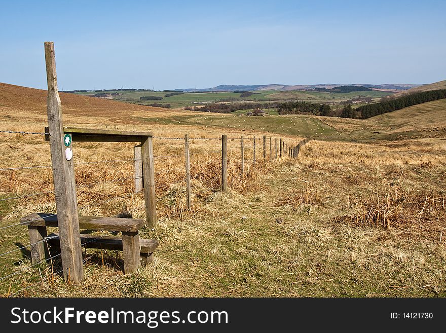 A landscape of Northumbria. With rock outcrops in the foreground.fields and farm in the midground and hills in the background. A landscape of Northumbria. With rock outcrops in the foreground.fields and farm in the midground and hills in the background