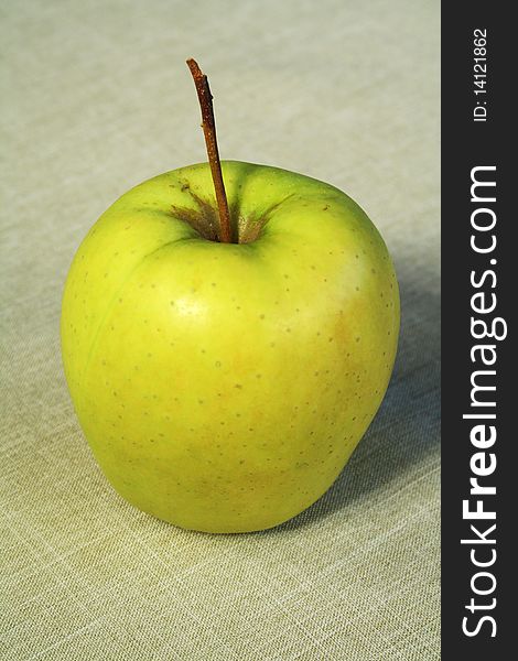 Green apple of a grade Golden, standing on a linen cloth. Green apple of a grade Golden, standing on a linen cloth